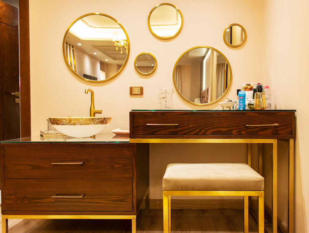 Master bedroom featuring luxury vanity unit and gold mirrors in a turnkey interior