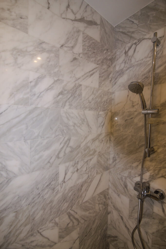 Renovated master bathroom with sleek marble tile work in Westown duplex project
